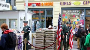 Police officers stand guard near sandbags and an American flag outside a store.