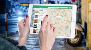 Person navigating on a tablet with a map and listings visible.