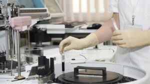 Lab technician handling samples with gloves in a scientific environment.