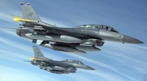 Two fighter jets flying in formation against a clear sky.