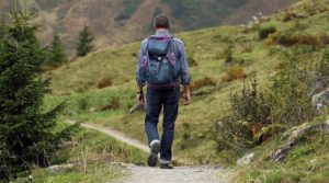 A person hiking on a trail with a backpack in a mountainous area.