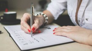 Person writing a letter with a pen on paper.