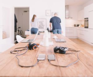 Two people working together in a modern kitchen with tech gadgets on the table.