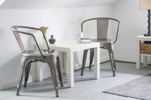Minimalist white dining table with metal chairs in a bright room.
