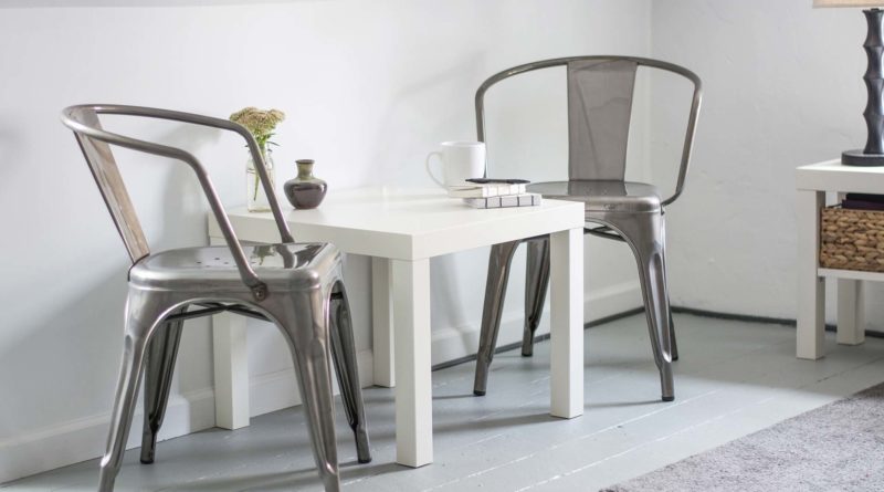 Minimalist white dining table with metal chairs in a bright room.