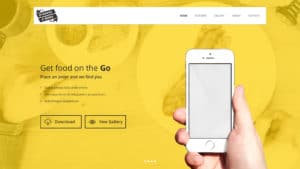 A hand holds a smartphone with a yellow-themed website interface in the background.