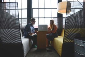 Two colleagues having a discussion in a modern office seating area.