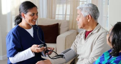 Nurse checking elderly man's blood pressure at home.