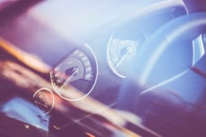 Blurred close-up of a car dashboard with speedometer and steering wheel.
