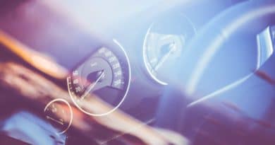 Blurred close-up of a car dashboard with speedometer and steering wheel.