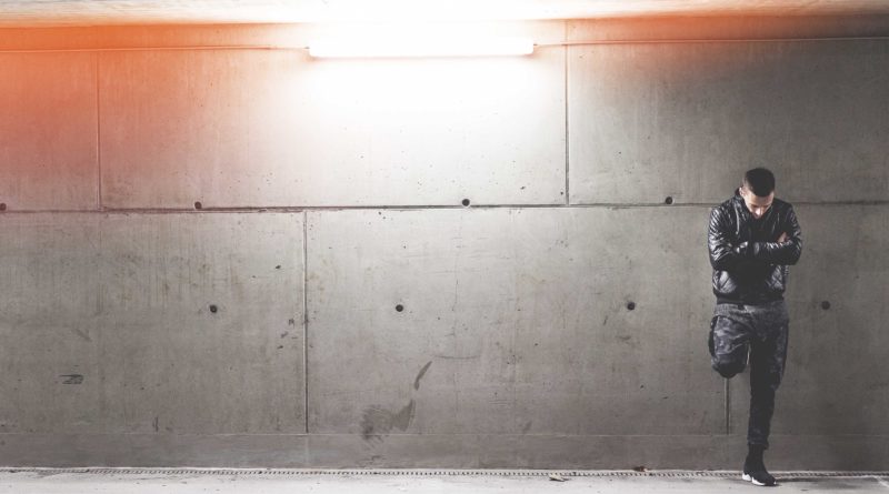 Empty concrete wall illuminated by overhead lights in a parking garage.