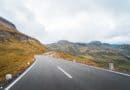 Empty winding mountain road under a cloudy sky.