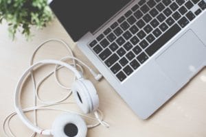 White headphones beside a laptop keyboard on a wooden desk.