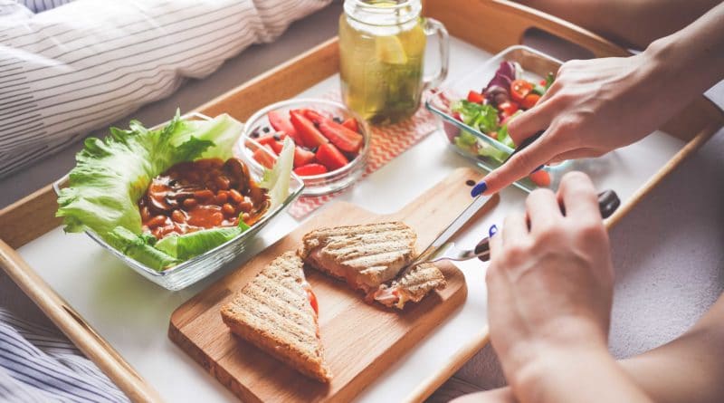 People enjoying a meal with grilled sandwiches and drinks at a cozy table.