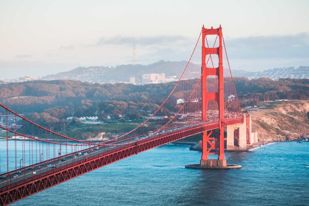 Golden Gate Bridge stretching over blue waters with hills in the background.