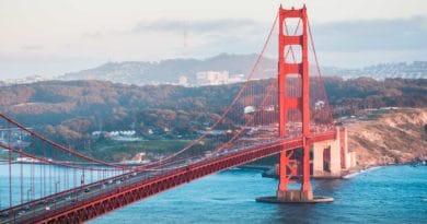 Golden Gate Bridge stretching over blue waters with hills in the background.