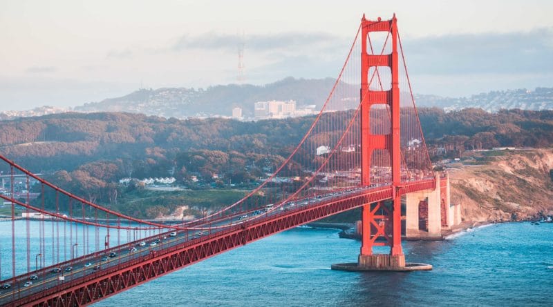 Golden Gate Bridge stretching over blue waters with hills in the background.