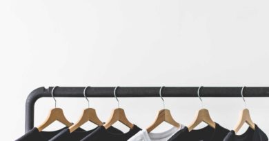 Black and white t-shirts hanging on wooden hangers on a clothing rack.