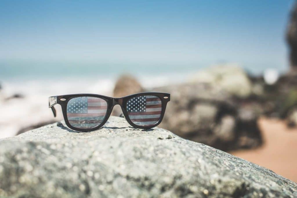 Sunglasses reflecting a scenic ocean view with rocks.