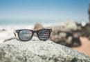 Sunglasses reflecting a scenic ocean view with rocks.