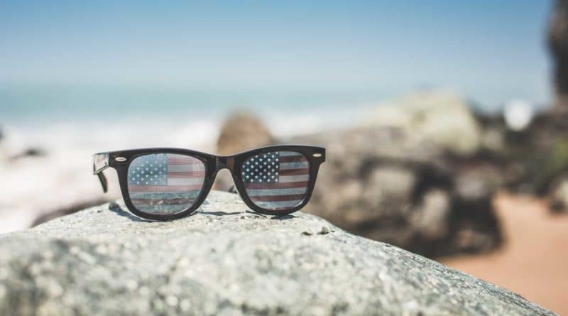 Sunglasses reflecting a scenic ocean view with rocks.
