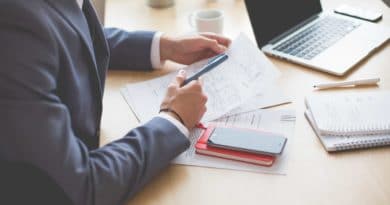 Businessperson analyzing financial data with documents and laptop.