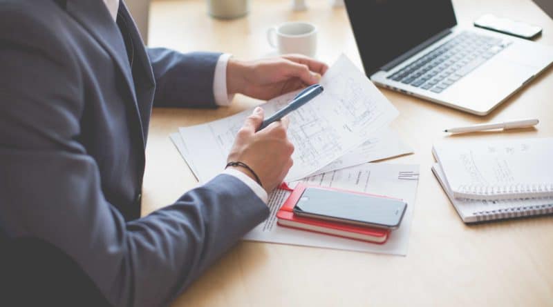 Businessperson analyzing financial data with documents and laptop.