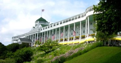 Historic Grand Hotel with a large veranda and American flags on a sunny day.