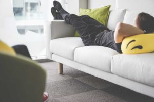 Person relaxing on a white couch indoors.
