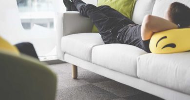 Person relaxing on a white couch indoors.