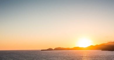 Sunset over a calm ocean with distant islands.