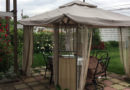 A cozy outdoor gazebo with patio furniture and flowers.