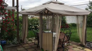 A cozy outdoor gazebo with patio furniture and flowers.