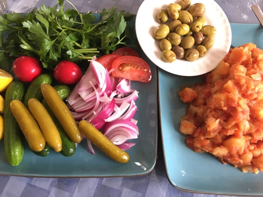 A plate of fresh vegetables, pickles, and olives.