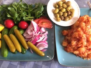 A plate of fresh vegetables, pickles, and olives.