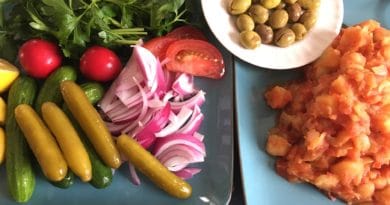 A plate of fresh vegetables, pickles, and olives.