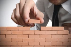 Person stacking small bricks to build a wall.