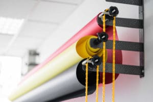 Colorful rolls of fabric hanging with yellow strings.