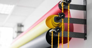 Colorful rolls of fabric hanging with yellow strings.