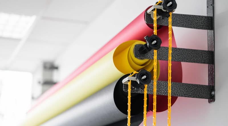 Colorful rolls of fabric hanging with yellow strings.