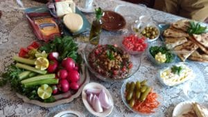 A table filled with fresh vegetables, dips, and olives.