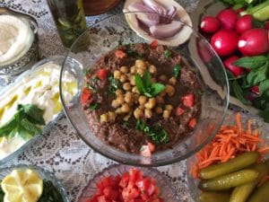 A colorful dish topped with chickpeas and herbs, surrounded by fresh ingredients.