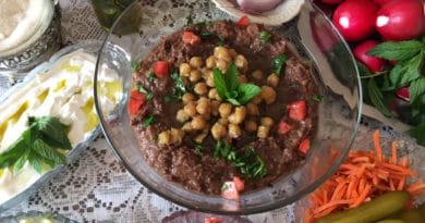 A colorful dish topped with chickpeas and herbs, surrounded by fresh ingredients.