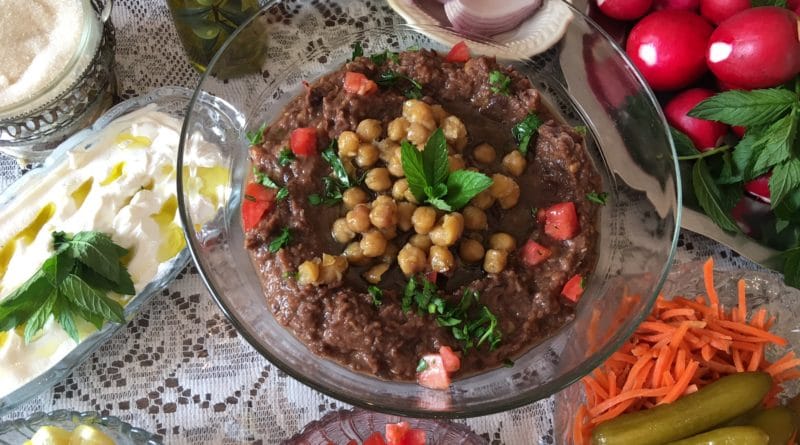 A colorful dish topped with chickpeas and herbs, surrounded by fresh ingredients.