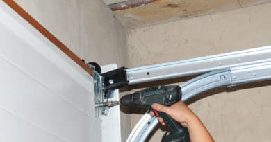 Person using a power drill to install a garage door hinge.