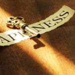 A vintage key casting a shadow over the word 'Happiness'.