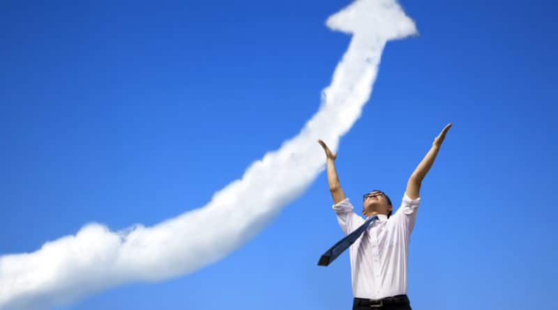 A woman celebrating under a sky with an upward arrow cloud.