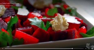 Close-up of beet salad with creamy dressing and parsley garnish.