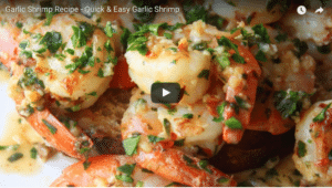 Close-up of garlic shrimp garnished with herbs on a plate.
