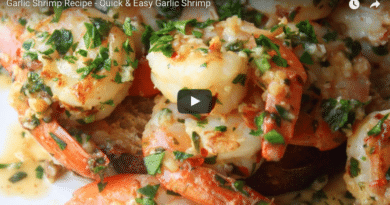 Close-up of garlic shrimp garnished with herbs on a plate.